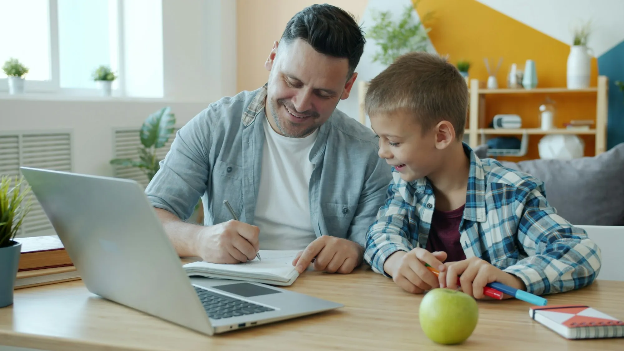 Father and son working on homework together at a laptop