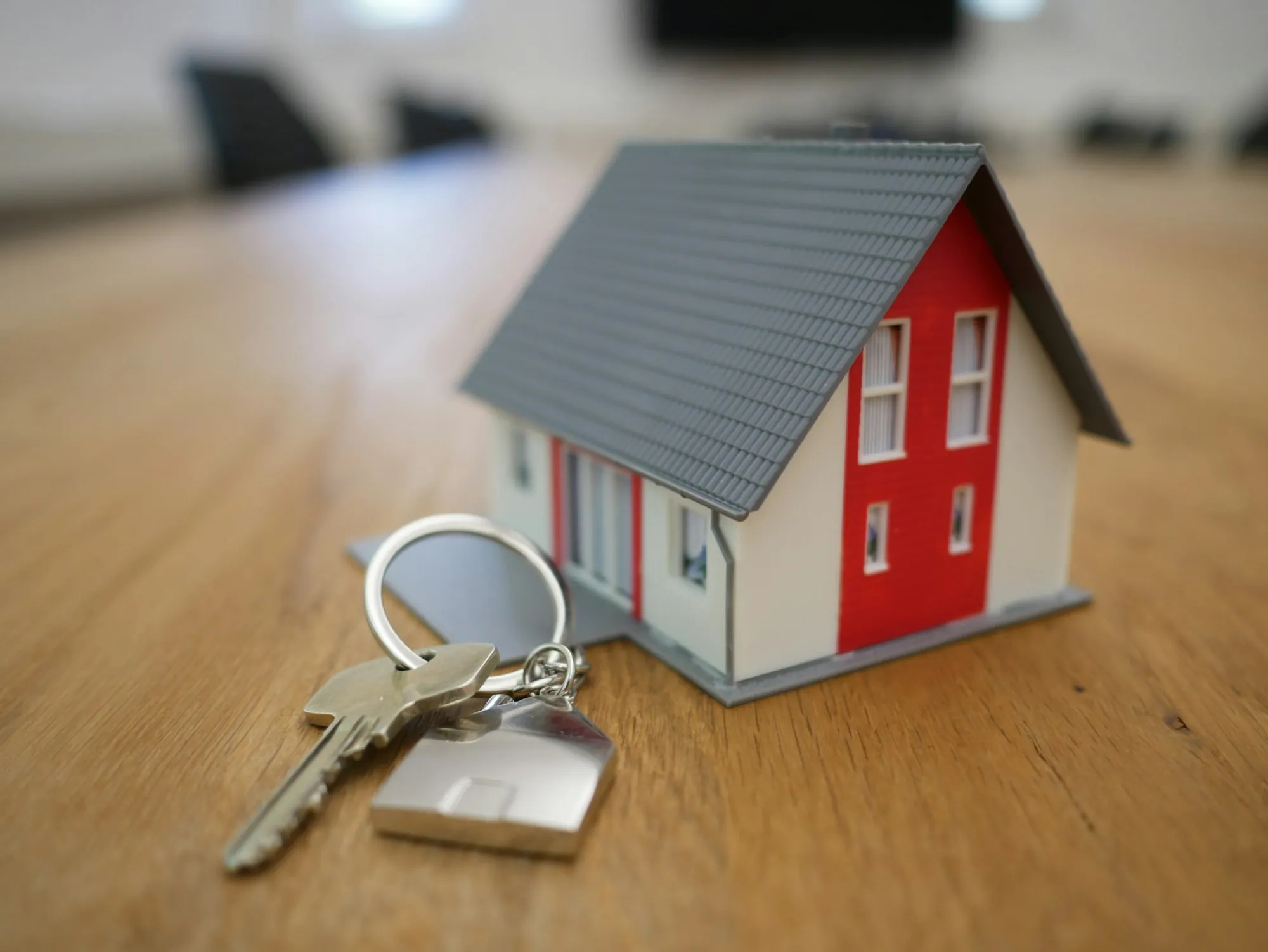 Model house with house keys on a wooden table